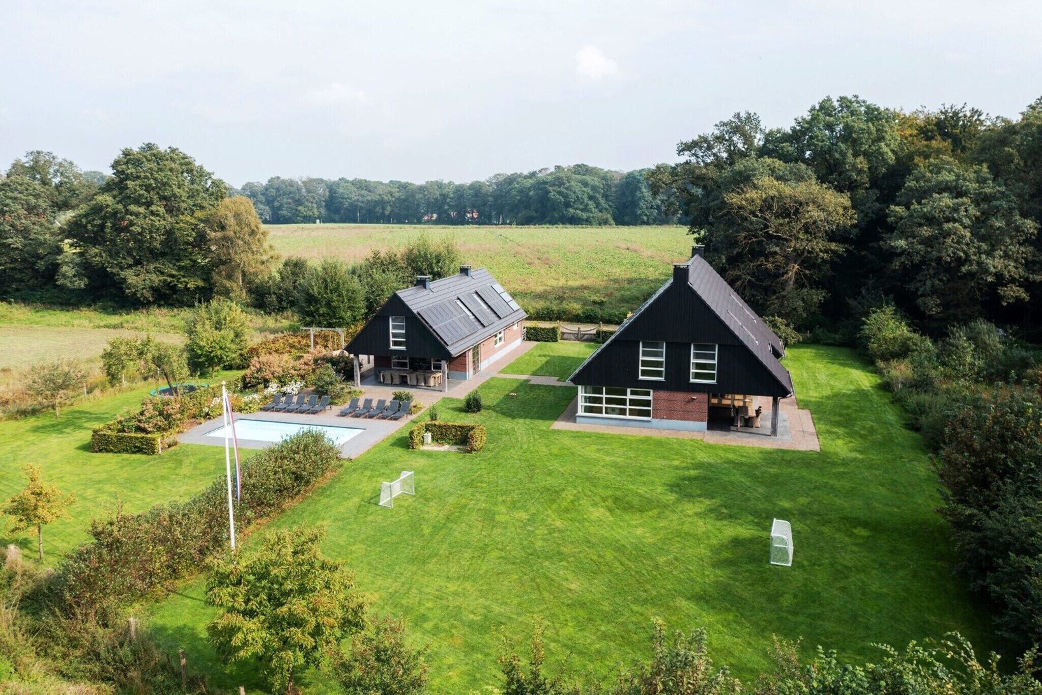 A large property with two main buildings, a swimming pool, and a well-maintained lawn.