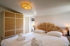 A hotel room with a bed, a large wardrobe, a wicker headboard, and a ceiling light fixture. - Holiday Home Near North Sea for 6 (Sint Maarten)