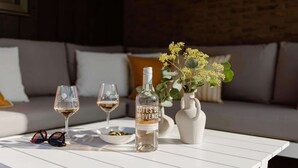 A table with a bottle of wine, two glasses, a bowl of olives, a vase with flowers, and a pair of sunglasses. - Holiday Home Near North Sea for 6 (Sint Maarten)