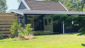 Ein modernes Haus mit Satteldach, Glastür und gepflegtem Rasen.