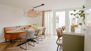 A dining area with a round table, chairs, a bench, and a hanging light fixture. - Modern Dune Retreat with Garden (Sint Maarten)