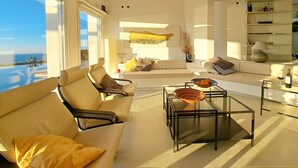 Una sala de estar moderna con un sofá, sillones y una mesa de centro de vidrio.