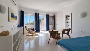 Una habitación moderna y bien iluminada con una cama, un escritorio y dos sillas de mimbre.