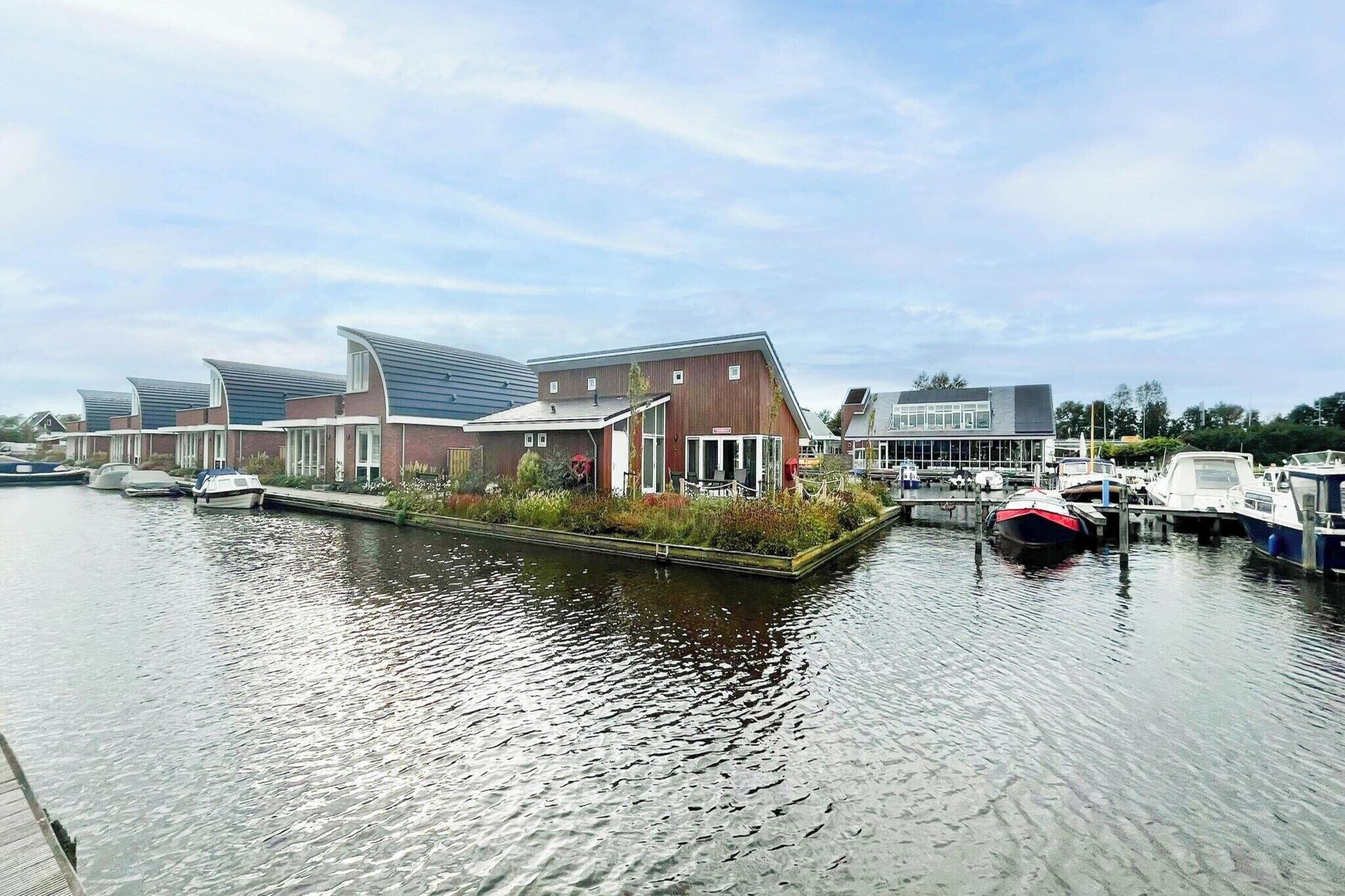 A canal-side building with a dock, boats, and a clear sky.