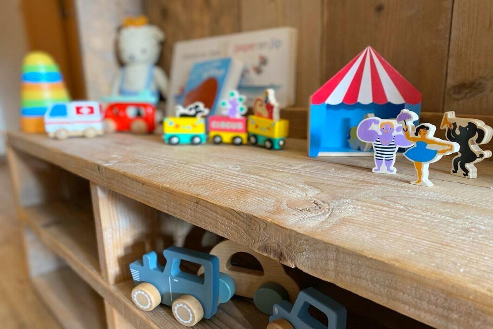 Een houten plank met diverse speelgoed en een klein huisje.