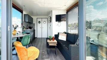 Ein modernes Interieur mit Essbereich, Sofa, Fernseher und Küche.