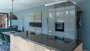 A modern kitchen with a large island, stainless steel appliances, and a minimalist design. - Wellness Villa with Private Hot Tub (Oosterhout)