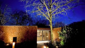 A modern building with a brick exterior, a glass door entrance, and a tree in the foreground. - Wellness Villa with Private Hot Tub (Oosterhout)