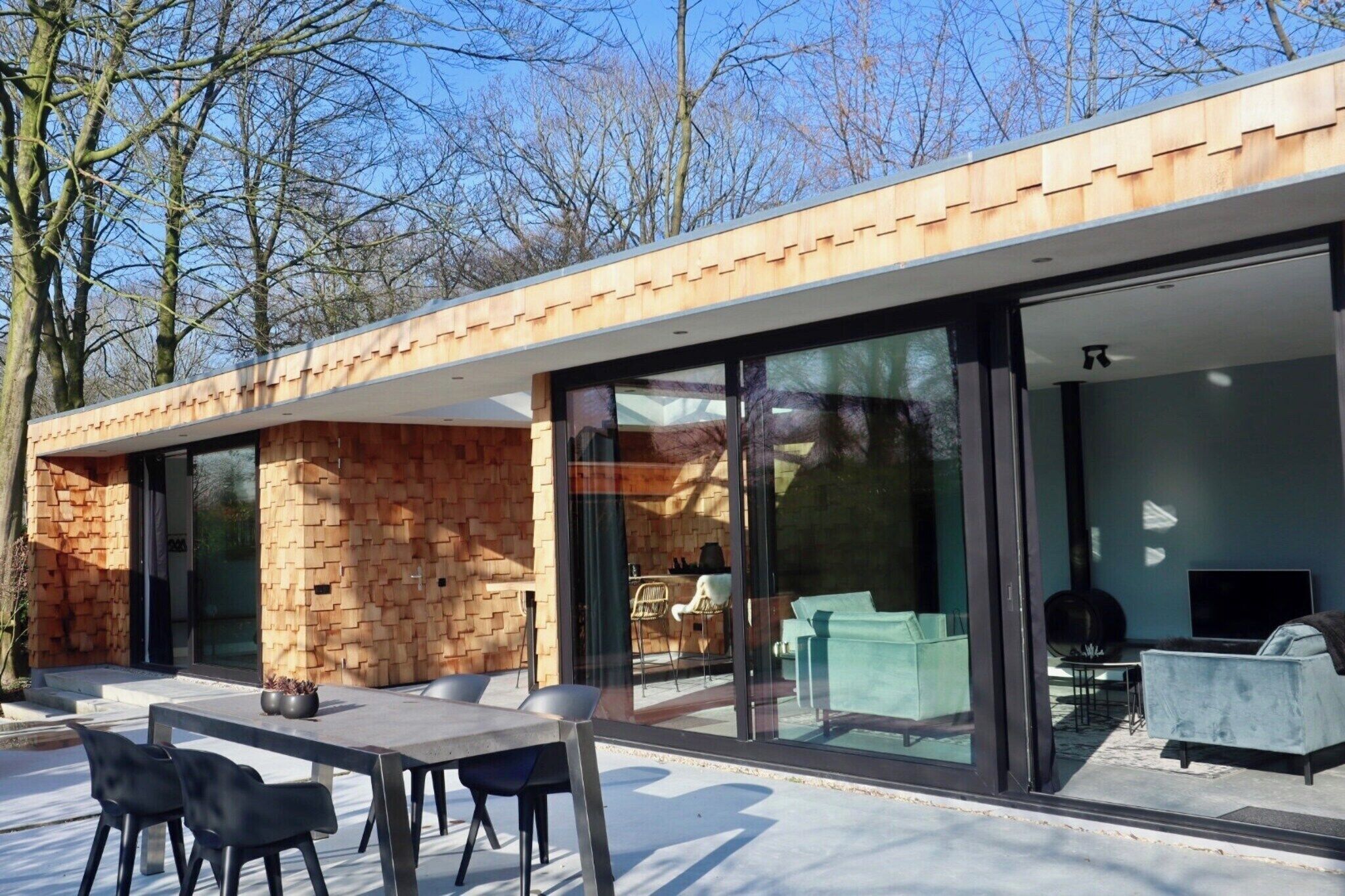 A modern house with a brick exterior, large glass doors, and a patio with outdoor furniture.