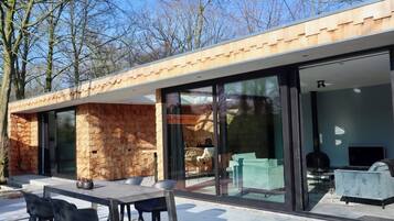 A modern house with a brick exterior, large glass doors, and a patio with outdoor furniture.