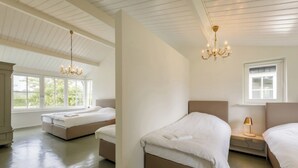 Habitación de hotel con dos camas, un candelabro, un ventanal y vistas al exterior.