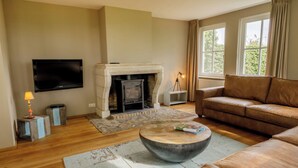 Una sala de estar con chimenea, un sofá, un televisor y una lámpara.