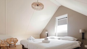 Un dormitorio con cama, dos lámparas de pared, una lámpara de techo y un ventanal con persianas.