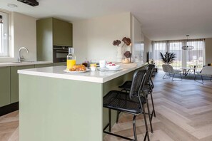 A modern kitchen with a central island, a dining area with a table and chairs, and a view of the outdoors. - Coastal Home with Garden for 6 (Sint Maarten)