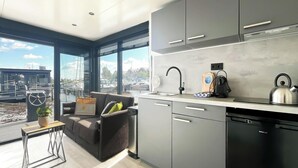 Une cuisine moderne avec des meubles gris, un lave-vaisselle noir et une fenêtre donnant sur un port de plaisance.