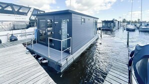 Une structure flottante dotée d’un quai, d’un drapeau, et d’un bateau nommé « Carpe Diem » en arrière-plan.