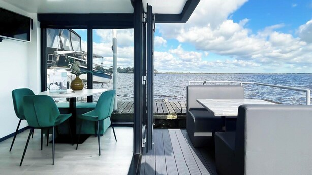 Une terrasse moderne avec une table et des chaises, un canapé et une vue sur l’eau.