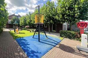 Un parque infantil con una estructura de escalada, un pequeño refugio y un flotador salvavidas rojo.