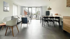 Een moderne woonkamer met een bank, stoelen, een eettafel en een televisie.