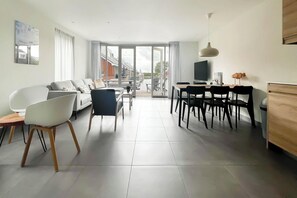 Een moderne woonkamer met een bank, stoelen, een eettafel en een televisie.