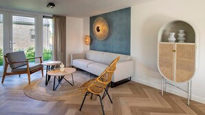 A modern living room with a sofa, two chairs, a coffee table, a rattan chair, a decorative wall piece, and a rattan cabinet. - 6-Guest Holiday Home with Terrace (Sint Maarten)