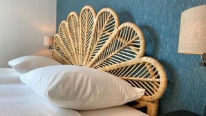 A bed with a woven headboard, white bedding, and a wall-mounted lamp. - 6-Guest Holiday Home with Terrace (Sint Maarten)