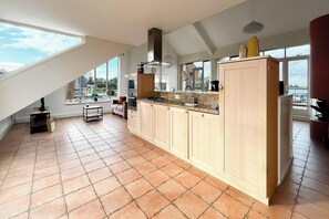 A modern kitchen with a large island, a built-in oven, and a large window providing a view of the outdoors. - Penthouse with Lake View Terrace (Uitgeest)