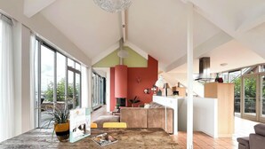 A modern interior with large windows, a wooden table, and a kitchen area. - Penthouse with Lake View Terrace (Uitgeest)