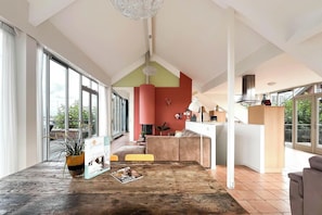 A modern interior with large windows, a wooden table, and a kitchen area. - Penthouse with Lake View Terrace (Uitgeest)