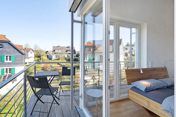 A balcony with a bed, a table, and chairs.