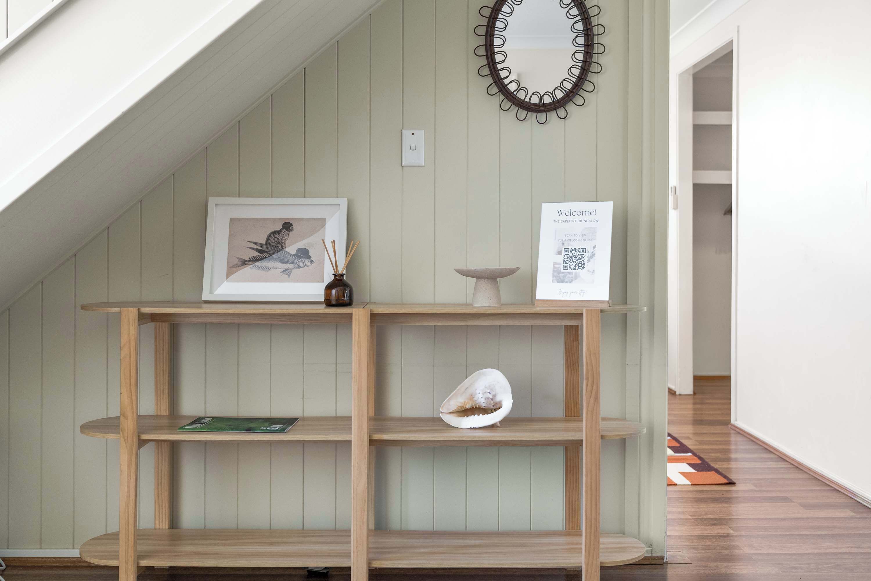 A wooden console table with a framed picture, a vase, and a decorative shell.
