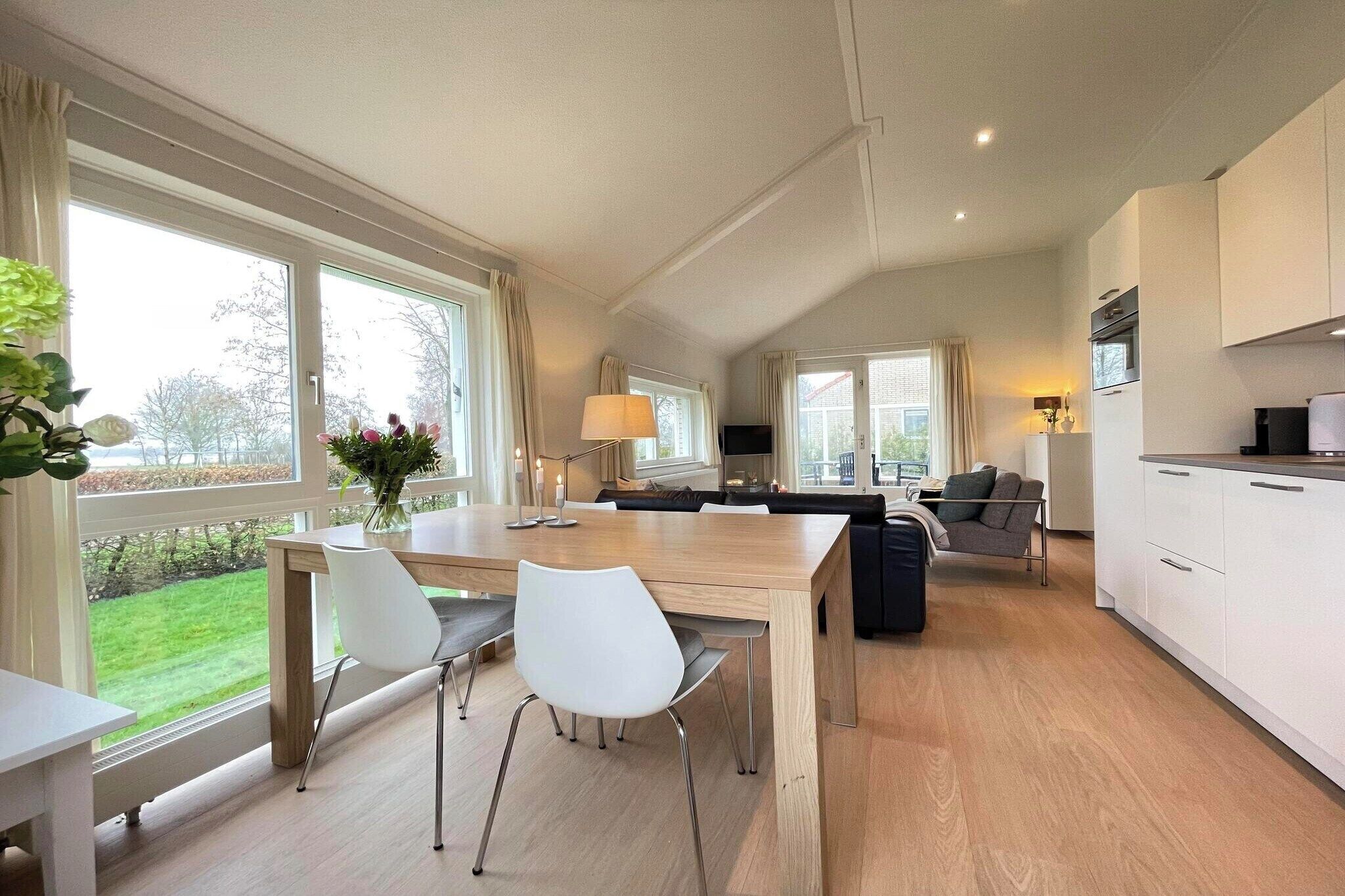 A modern kitchen with a dining area, large windows, and a view of the outdoors.