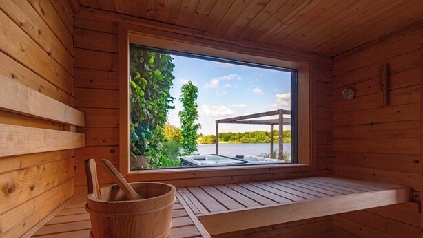 Puinen sauna, jossa on ikkuna, puinen ämpäri ja penkki.