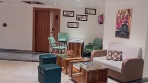 A lobby with a sofa, chairs, a coffee table, and framed pictures on the wall. - Hotel KAMA (Danapur)
