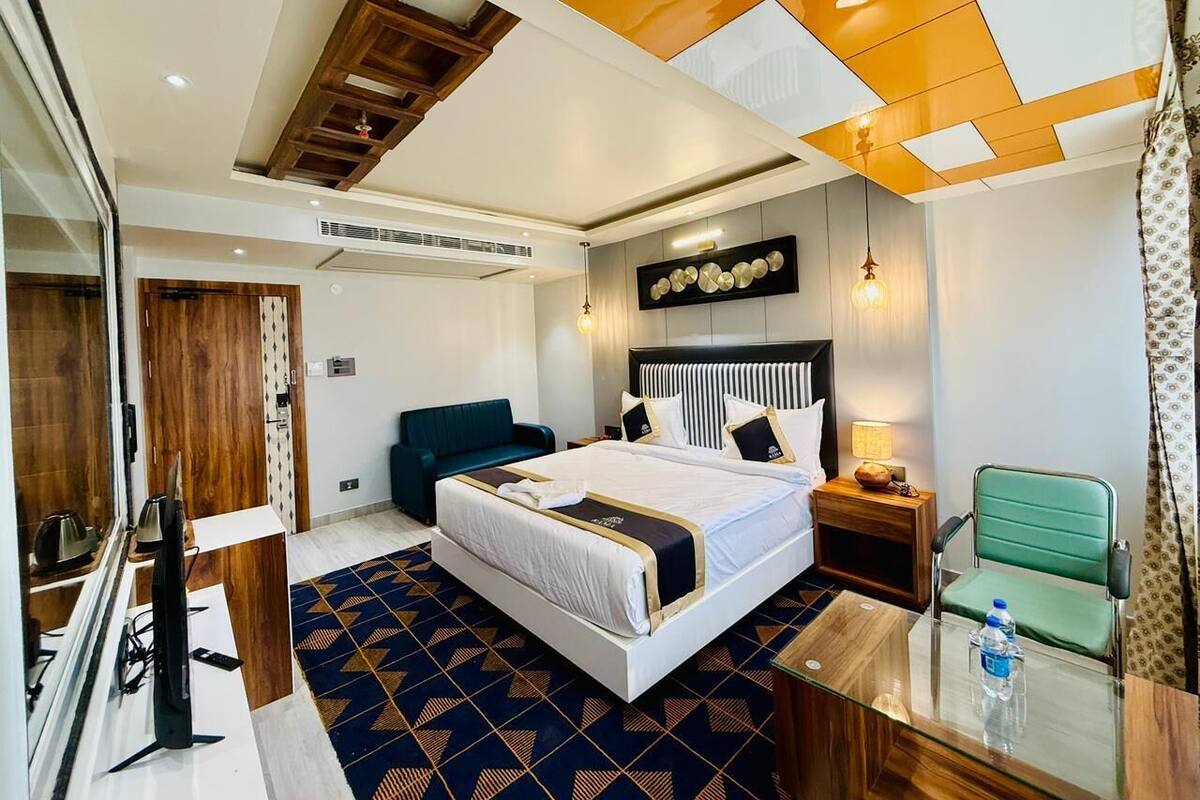 A hotel room with a large bed, a desk, a chair, a TV, and a window.