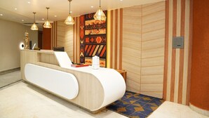 A reception desk with a modern design, a patterned wall, and pendant lighting. - Hotel KAMA (Danapur)