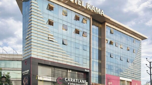 A modern hotel with a prominent 'HOTEL KAMA' sign, a glass facade, and a 'CARATLANE' advertisement on the lower level. - Hotel KAMA (Danapur)