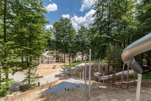 A playground with slides and climbing structures surrounded by trees.