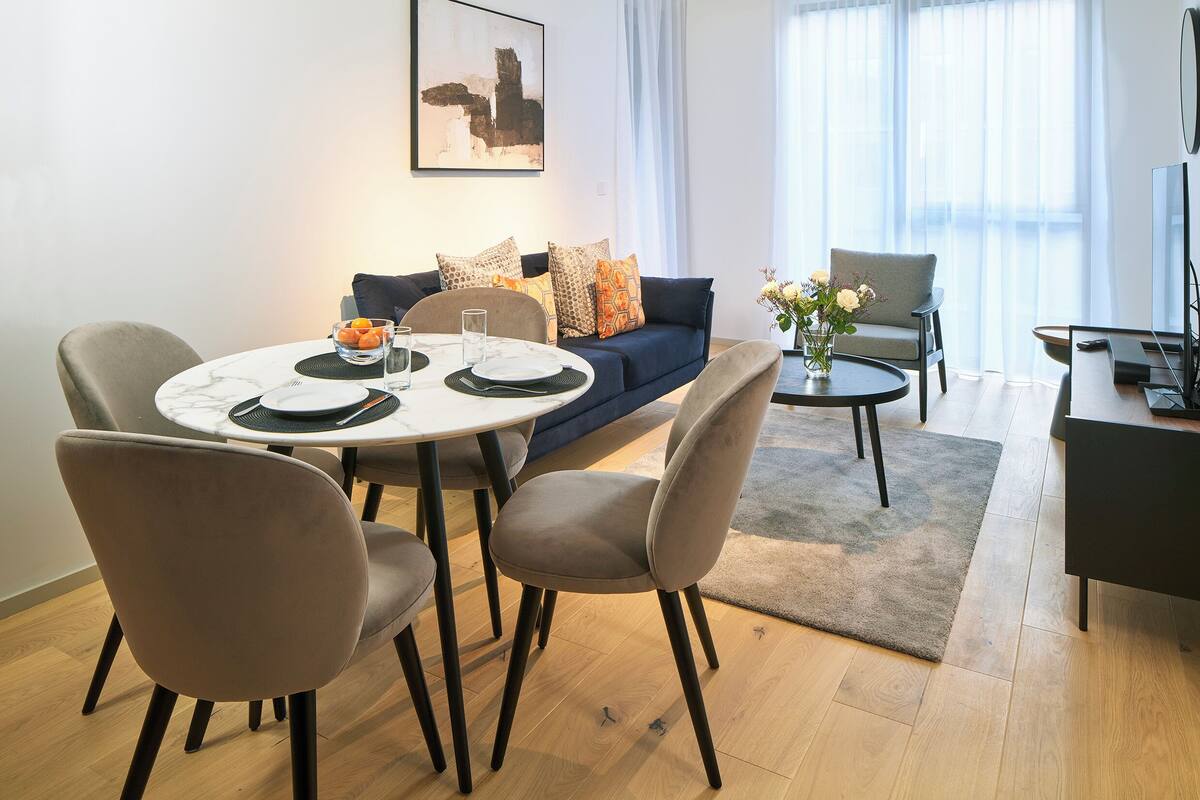 A modern living room with a dining area, a sofa, a coffee table, and a TV stand.
