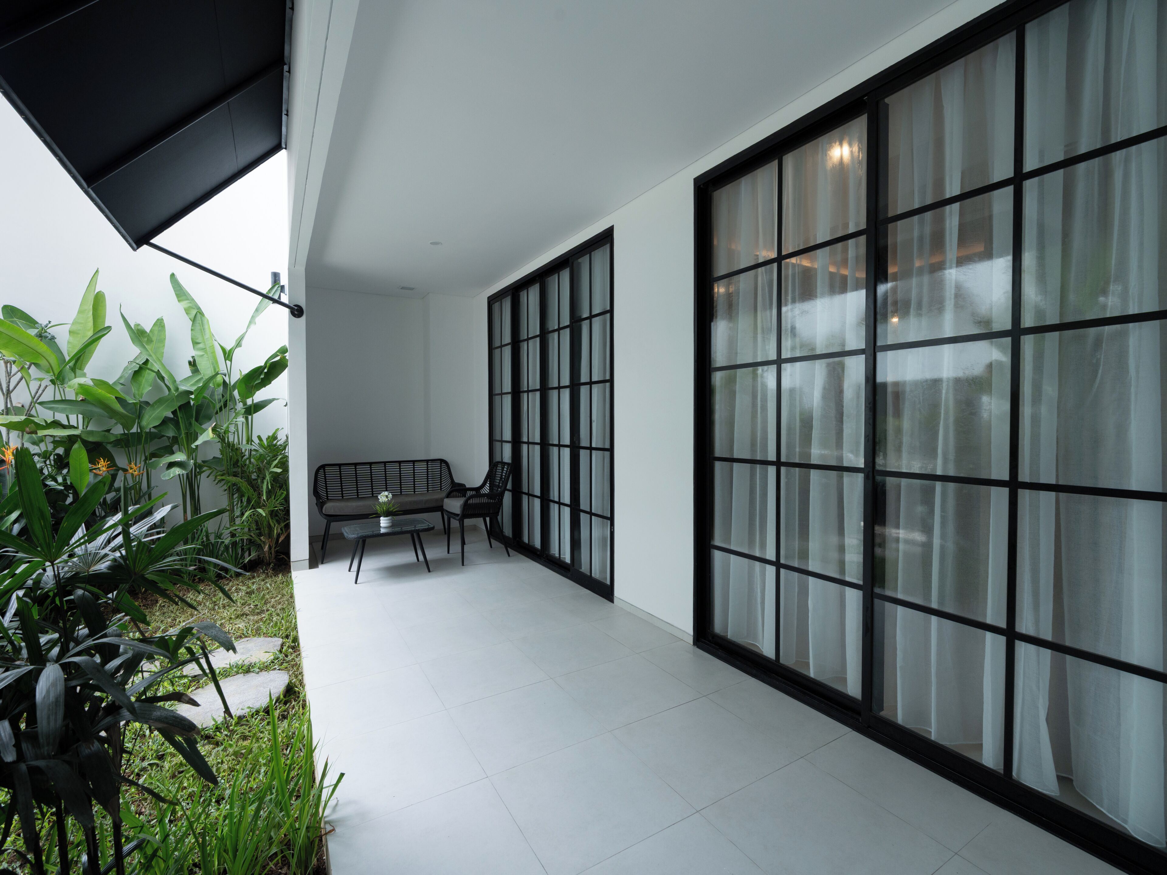 A modern interior with a seating area, large windows, and indoor plants.