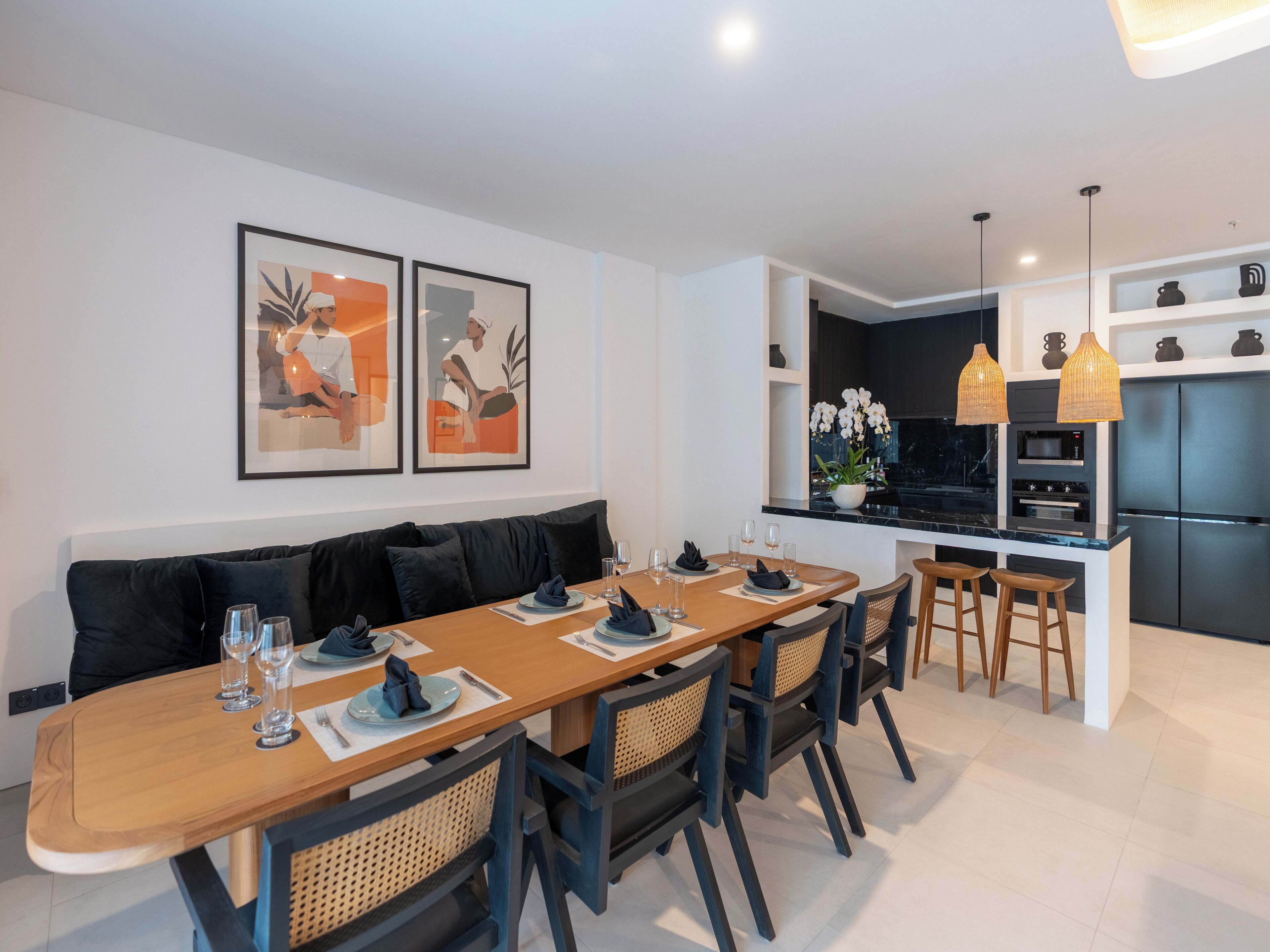 A modern kitchen with a black refrigerator, built-in oven, and a marble countertop.