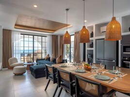 A modern dining area with a large table set for six, surrounded by wicker chairs.