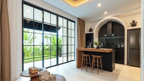 A modern kitchen with a large window, a dining area with stools, and a small island.