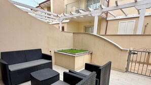 Um pátio com móveis de vime, uma piscina pequena e uma escadaria.