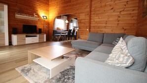 A modern log cabin interior with a living room, dining area, and kitchen.