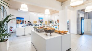 Eine moderne Hotelhalle mit Selbstbedienungsbereich, weißen Wänden und Deckenleuchten.