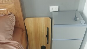 Pieni huone, jossa on sänky, puinen kaappi ja jääkaappi.