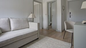 Una sala moderna con un sofá, un sillón, una lámpara y un escritorio.