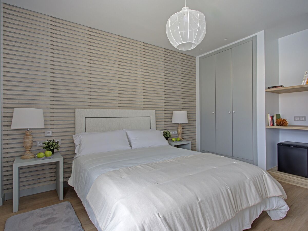 A bedroom with a bed, bedside tables, a lamp, a wardrobe, and a small shelf.