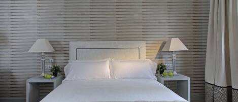 A neatly made bed with white linens, two bedside tables with lamps, and a headboard.